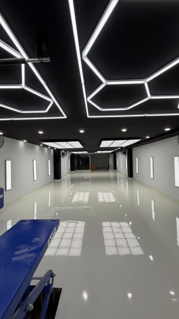 Ceiling installation of Newon Lighting hexagonal LED panels and 2x2 ft surface-mounted LED panels providing shadow-free illumination for car detailing.