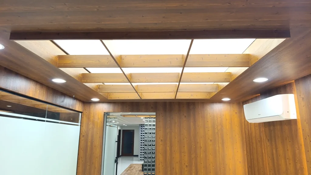 White stretch fabric ceiling light in corporate lounge area with wooden beams and recessed downlights, Islamabad